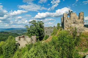 Obraz premium Andelska hora, Czech Republic - August 11 2018: Remains of the stone castle from 15th century standing on a hill with green trees and scenic view into the countryside. Sunny summer day with blue sky.