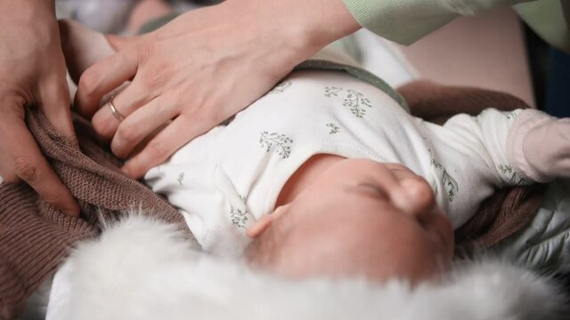 A woman is dressing her newborn baby. View from above.