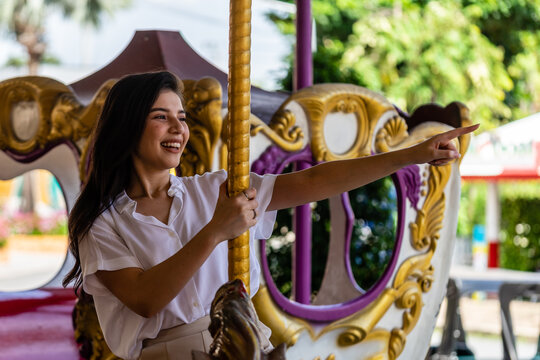 The asian young woman happily smiling and sitting in the carousel of the amusement park