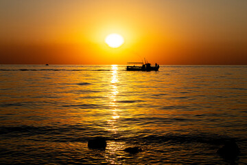 Silhouette of a fishing boat in the sea at sunset
