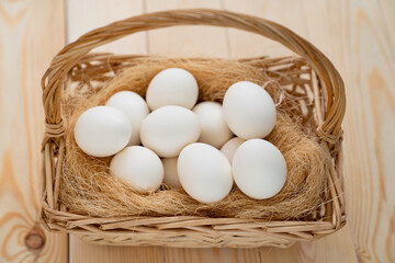 White eggs in the basket scattered on wooden table. the farm's products.