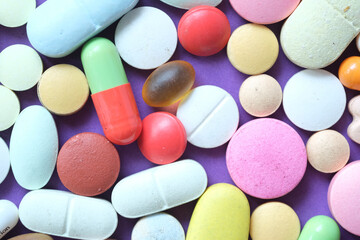 Close up of many colorful pills and capsules on color background 