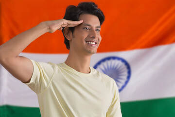 young man saluting while standing in front  of indian flag, independence day	