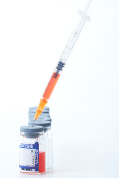 Covid-19 Written vaccine bottle with a red liquid and taking the vaccine from it with a syringe