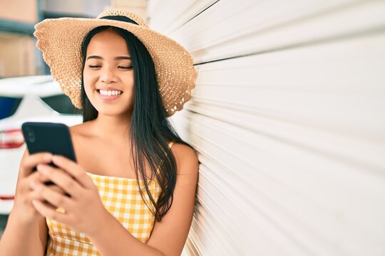 Young asian girl smiling happy at the city using smartphone