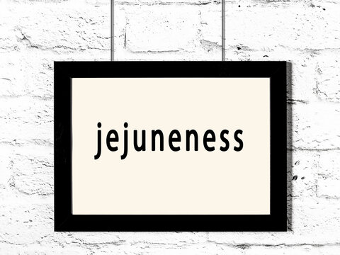 Black frame hanging on white brick wall with inscription jejuneness