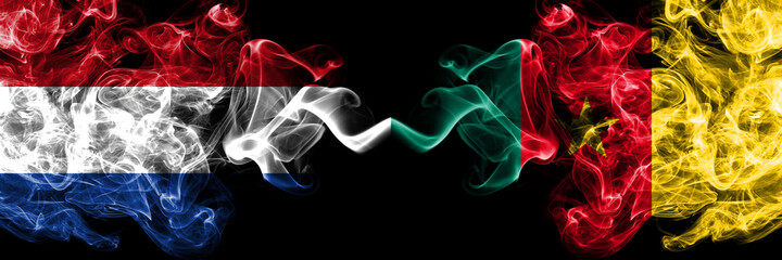 Obraz premium Netherlands vs Cameroon, Cameroonian smoky mystic flags placed side by side. Thick colored silky abstract smoke flags.