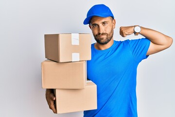 Handsome man with beard wearing courier uniform holding delivery packages strong person showing arm...