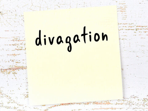 Yellow sticky note on wooden wall with handwritten word divagation