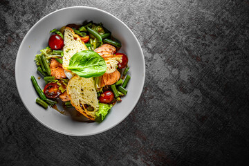 Green Bean Salad with Boiled Eggs, Salmon, Tomatoes and Arugula in a bowl on Dark grey black slate background
