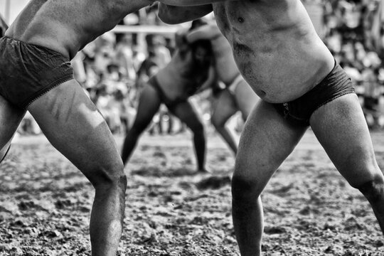 Midsection Of Men Wrestling In Mud