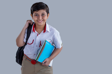 portrait of a school boy smiling with bag and books in hand 	