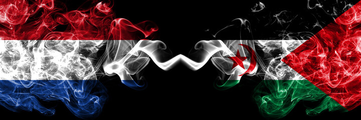 Netherlands vs Sahrawi smoky mystic flags placed side by side. Thick colored silky abstract smoke flags.