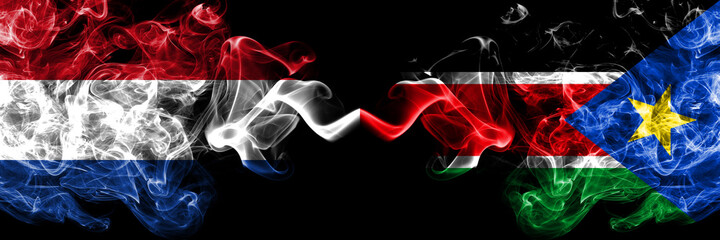 Netherlands vs South Sudan smoky mystic flags placed side by side. Thick colored silky abstract smoke flags.