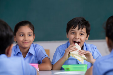 school boy eating sandwich in lunch 	