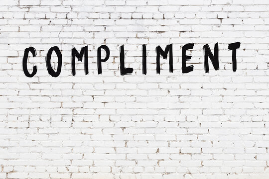 White wall with black paint inscription compliment on it