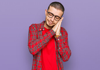 Hispanic young man wearing casual clothes sleeping tired dreaming and posing with hands together while smiling with closed eyes.