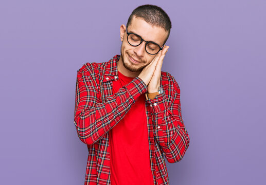 Hispanic young man wearing casual clothes sleeping tired dreaming and posing with hands together while smiling with closed eyes.