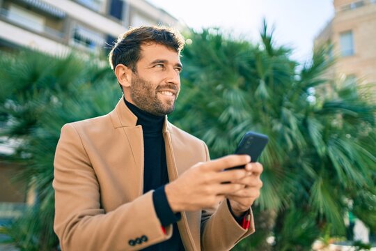 Handsome business man wearing elegant jacket using smartphone smiling happy outdoors