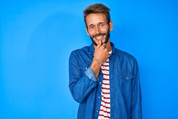 Handsome caucasian man with beard wearing casual clothes smiling looking confident at the camera with crossed arms and hand on chin. thinking positive.