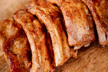 fried with spices pork ribs in a glass baking sheet on a wooden cutting board. cooked meat at home. Barbecue.
