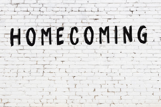 Inscription homecoming painted on white brick wall