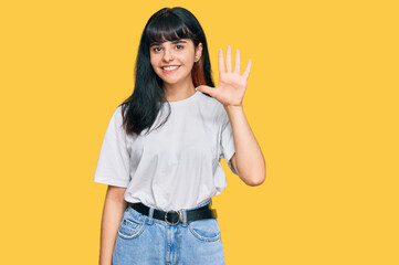 Young hispanic girl wearing casual clothes showing and pointing up with fingers number five while smiling confident and happy.