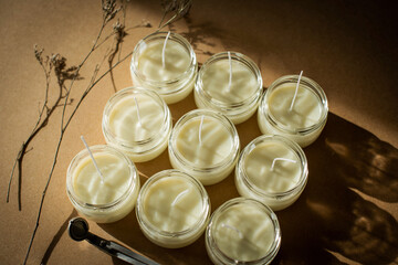 Handmade candle from paraffin and soy wax in glass with flowers and tools on craft background. Let flay. Candle making