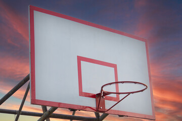 Basketball backboard with hoop on dramatic sunset background