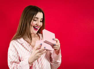 What a surprise. girl surprised excited holds gift box  on red background.