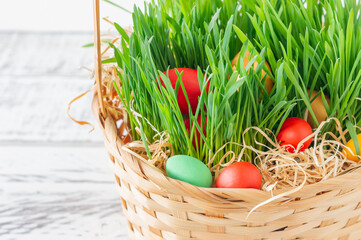 Hand-painted decorated Easter eggs in the basket on white wooden background, close up. Easter background