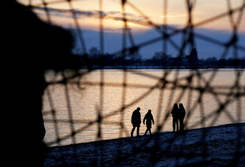 Spaziergänger am Elbstrand in Hamburg gesehen durch ein Gitter