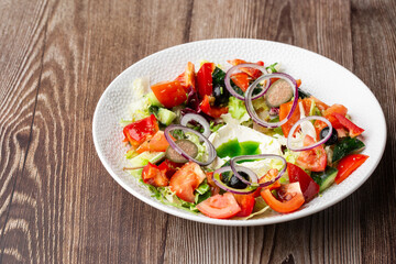 Greek salad with fresh vegetables: tomato, cucumber, red bel pepper, lettuce, onion, olives and...