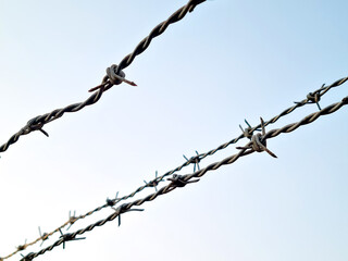 Closeup shot of barbed wires against the blue sky