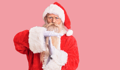 Old senior man with grey hair and long beard wearing traditional santa claus costume doing time out...