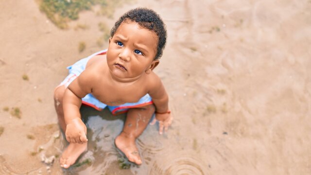 Adorable african american toddler sitting at the beach.