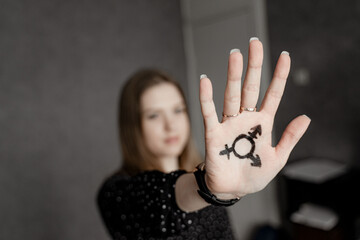 The girl shows on her hand the combined symbol of androgyne and bigender