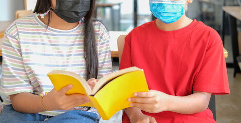 boy girl student wearing face mask studying reading book in library. learning education at school