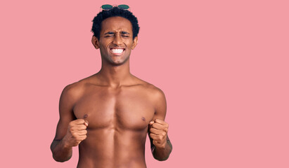 Fototapeta premium African handsome man wearing swimsuit and sunglasses excited for success with arms raised and eyes closed celebrating victory smiling. winner concept.