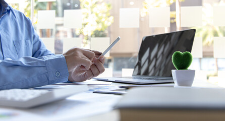 Finance workers are reviewing the company's financial data on a laptop and using smartphones to communicate or chat with the team at social distances, Working during the virus outbreak.