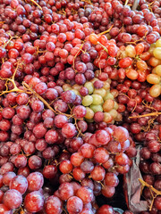 Closeup of bunches of purple grapes on market stall, with blurred background.