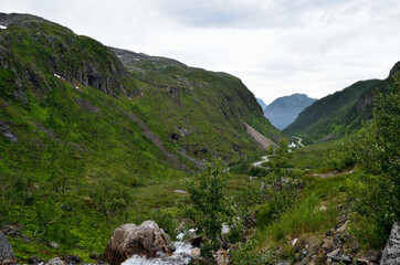 twisted road through mountain valley with sea in distance
