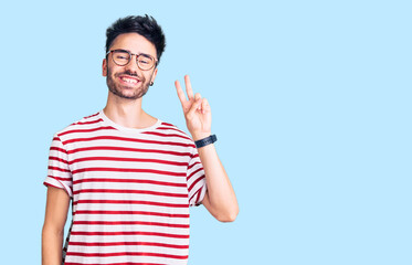 Young hispanic man wearing casual clothes smiling looking to the camera showing fingers doing victory sign. number two.