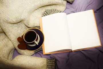 A cup of coffee, two gingerbread hearts and a blank open notebook on the bed. selective focus, copy space, softblurr effect