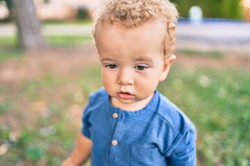 Cute and happy little boy having fun at the park on a sunny day. Beautiful blonde hair male toddler playing outdoors