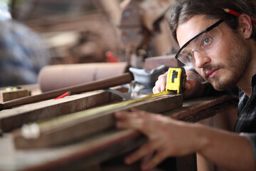 Carpenter, he is working in the workshop. Man at work on wood. Image of mature carpenter in the workshop, furniture making concept.
