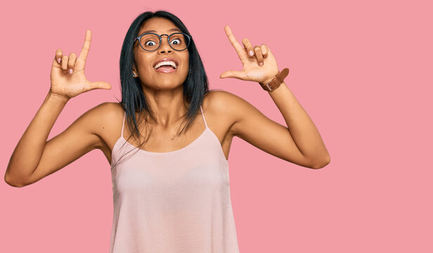 Young african american woman wearing casual clothes and glasses smiling amazed and surprised and pointing up with fingers and raised arms.