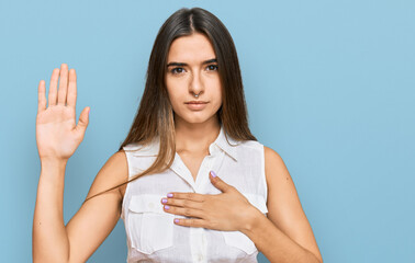 Young hispanic woman wearing casual clothes swearing with hand on chest and open palm, making a...