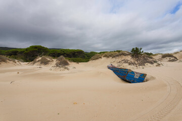 Fototapeta na wymiar The fisherman boat abandoned in the dunes of Baelo Claudia near Tarifa, Spain, during quarantine because of COVID-19 