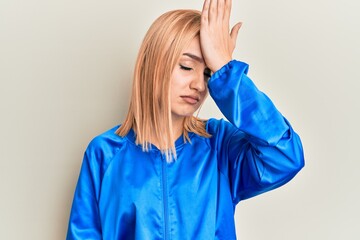 Beautiful caucasian woman wearing sportswear surprised with hand on head for mistake, remember...